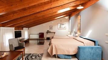 Un dormitorio acogedor en el ático con techo de madera, cama con cabecera azul, escritorio con silla y televisor.