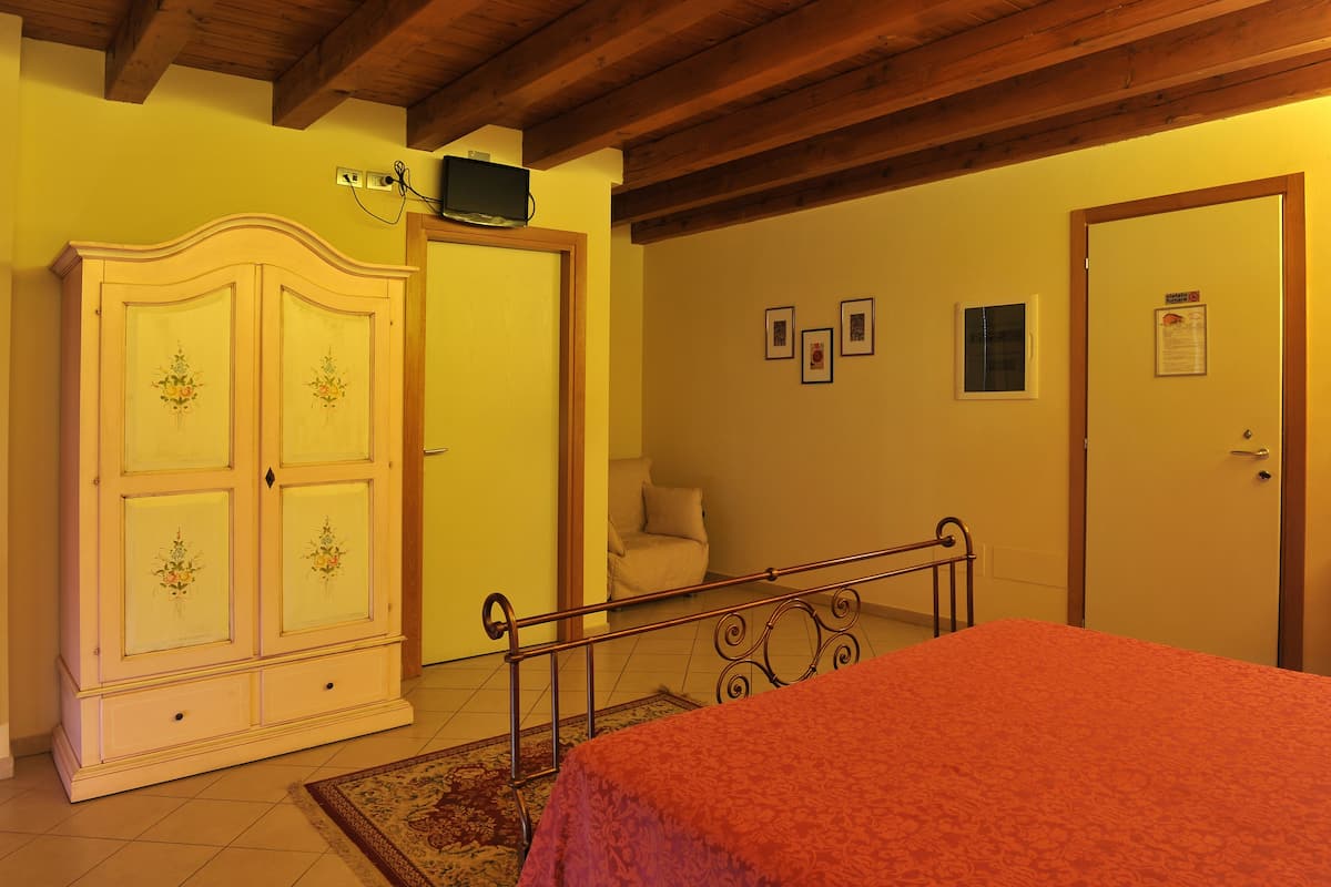 A bedroom with a bed, a wardrobe, a door, and a small window.