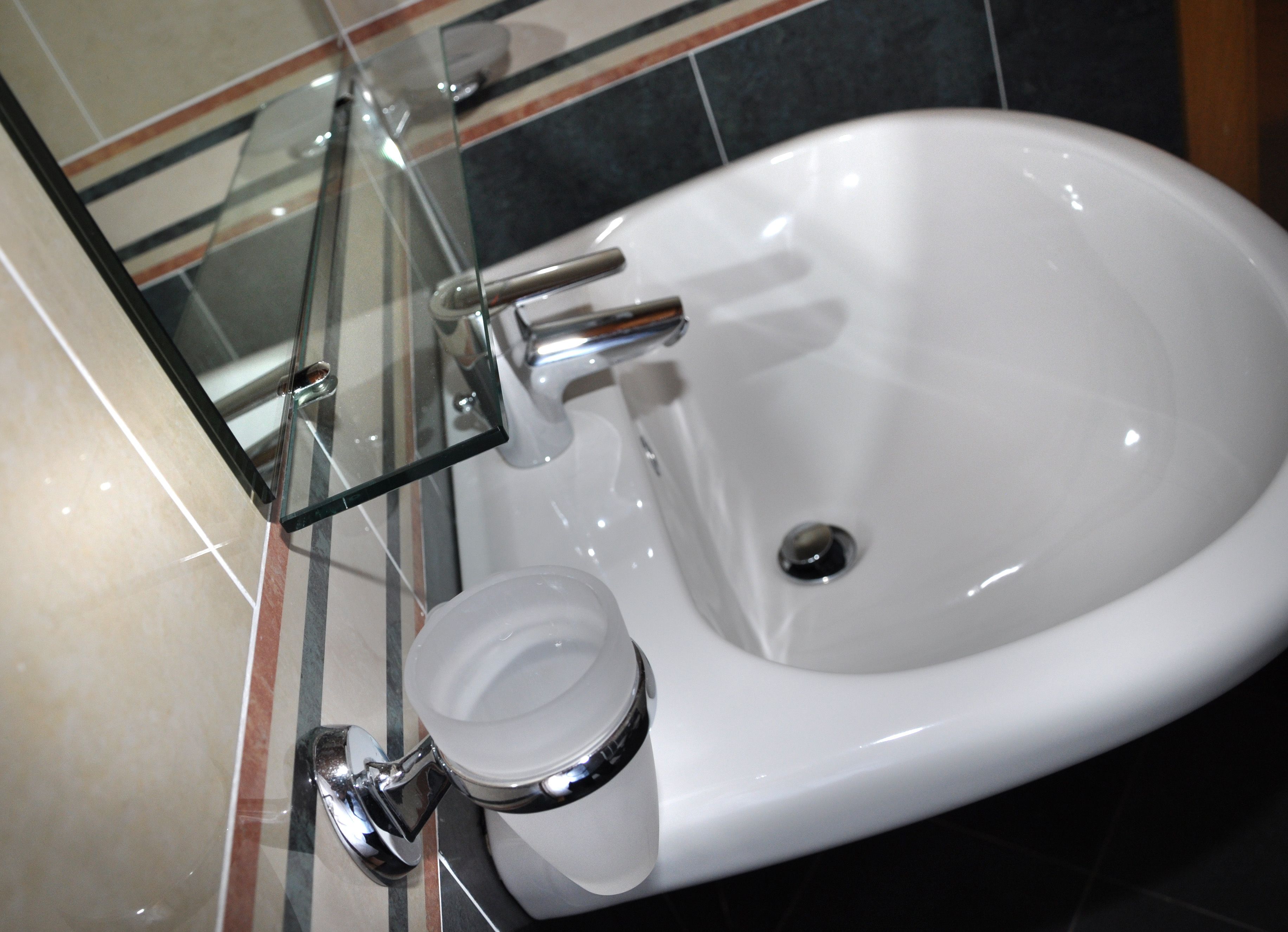 A white bathroom sink with a chrome faucet and a glass soap dispenser.