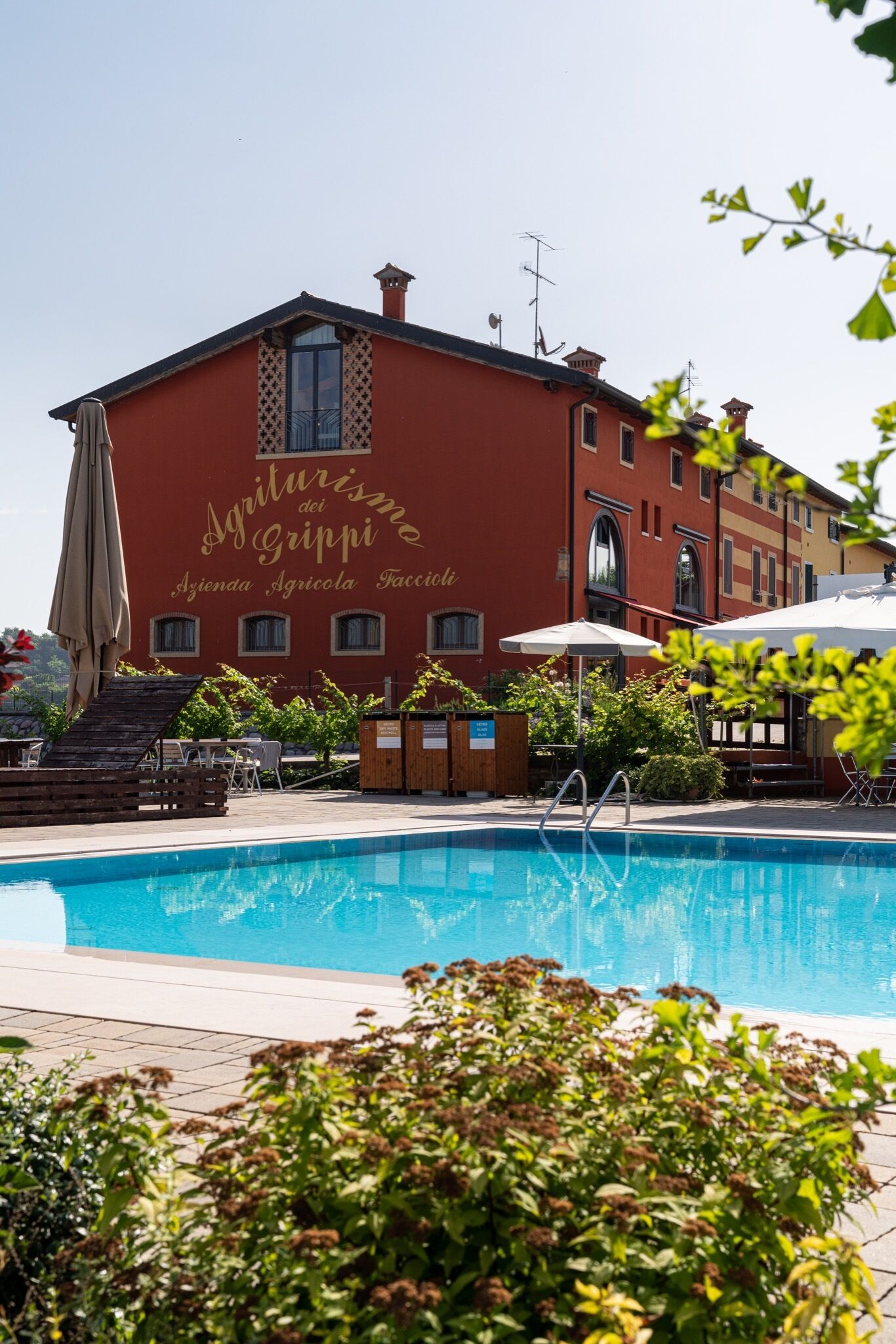 A red building with a swimming pool in front.