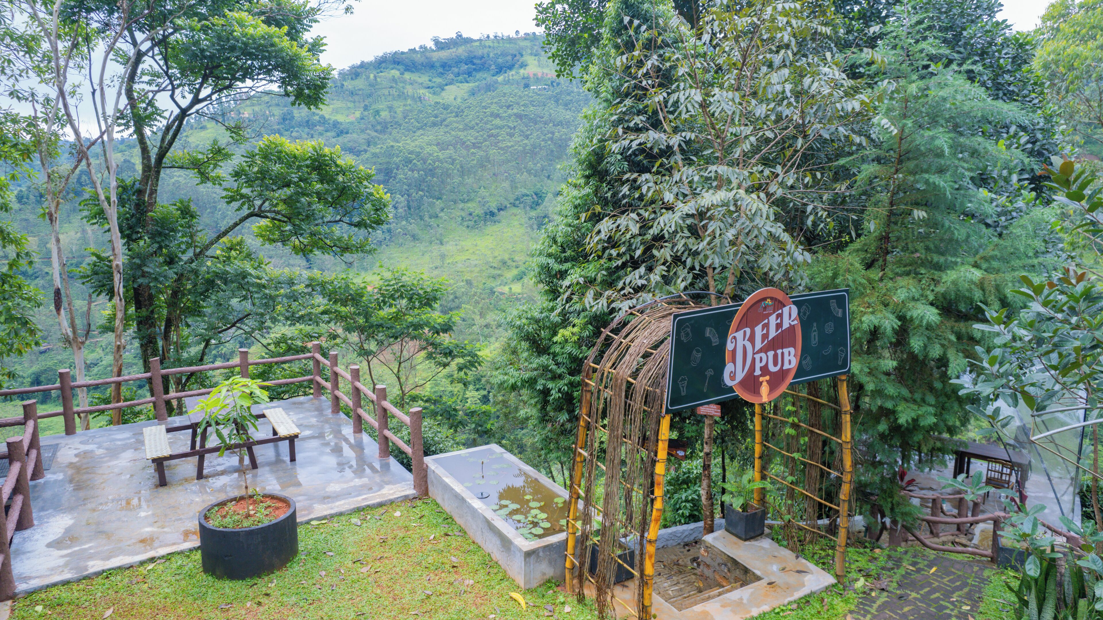 A scenic outdoor seating area with a 'Beer Pub' sign, surrounded by lush greenery and hills.