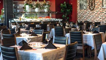 Een restaurant met meerdere tafels en stoelen, elk voorzien van wijnglazen en servetten.