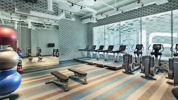 A gym with treadmills, elliptical machines, and exercise balls.