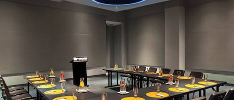 A conference room with a long table, chairs, and a podium.