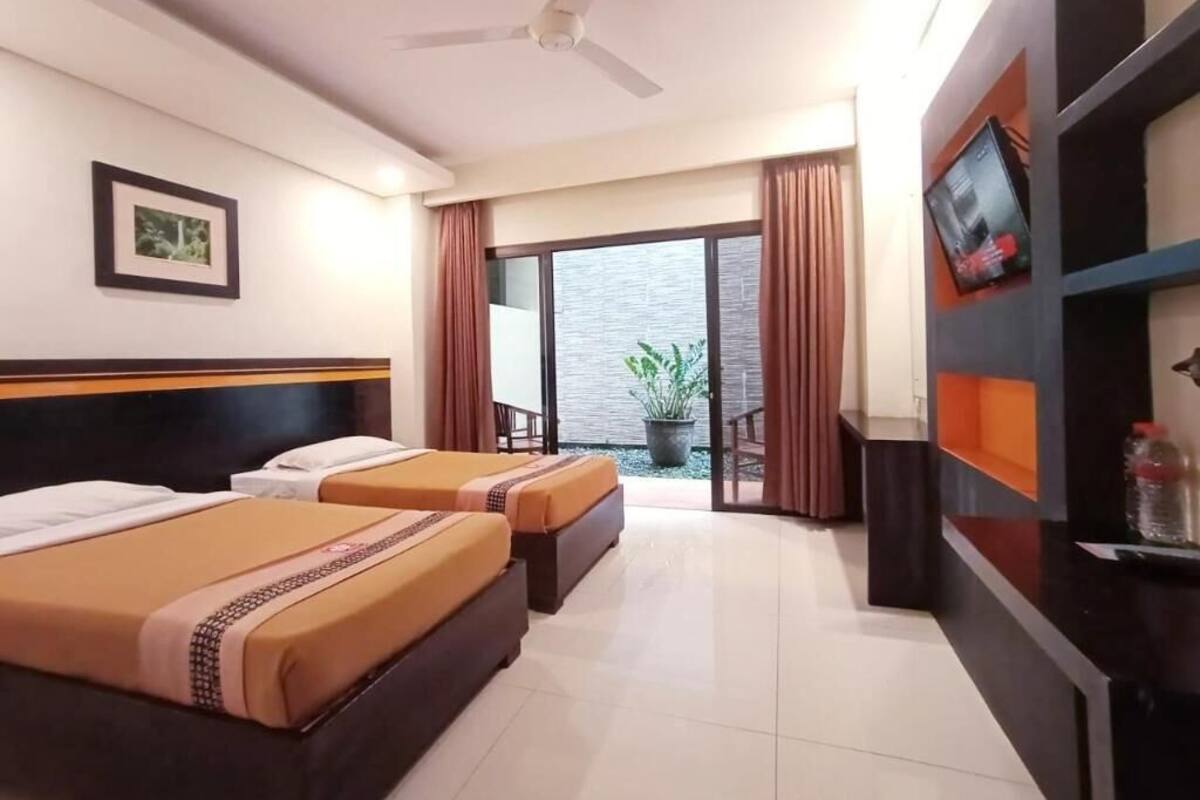 Une chambre d’hôtel avec deux lits, un ventilateur de plafond, un téléviseur fixé au mur et un balcon avec vue.