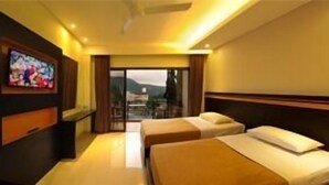 Habitación de hotel con dos camas, un televisor en la pared y vistas a las montañas desde la ventana.