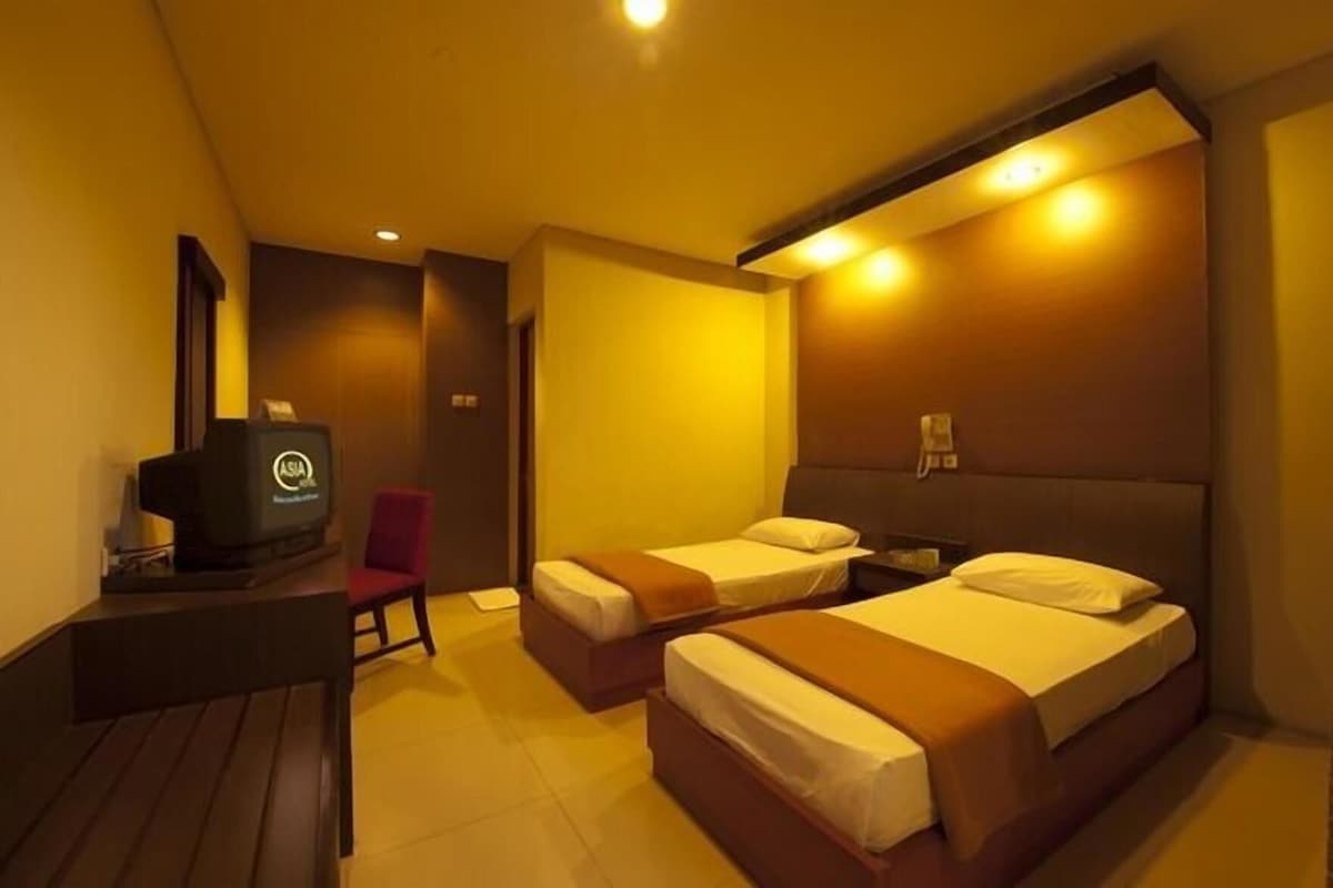 Une chambre d’hôtel avec deux lits, un bureau, une chaise et un mini-bar.