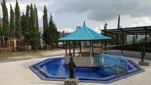 Una piscina con un quiosco, una estatua y una zona cubierta.