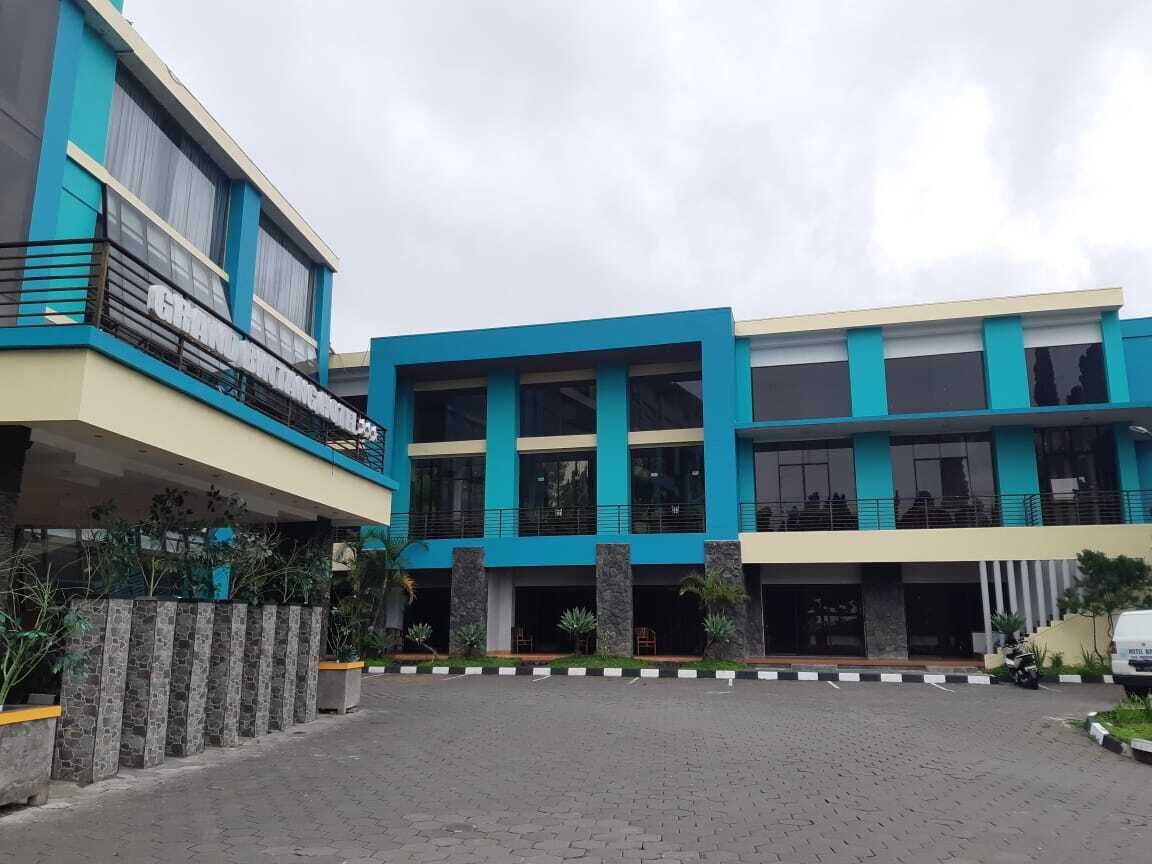 A modern building with a flat roof, large windows, and a paved entrance area.