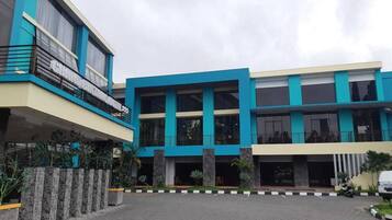 A modern building with a flat roof, large windows, and a paved entrance area.