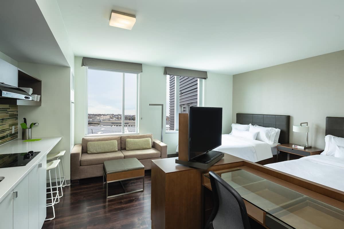 Une chambre d’hôtel équipée d’une kitchenette, d’un canapé, d’un lit, d’une télévision et d’un bureau.