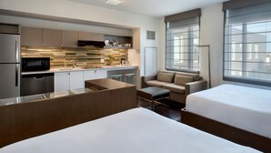 A modern hotel room with a kitchenette, two beds, a sofa, and large windows. - Element by Marriott Boston Seaport District (Boston)