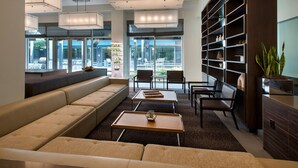 A modern lounge area with a sofa, tables, and a bookshelf. - Element by Marriott Boston Seaport District (Boston)