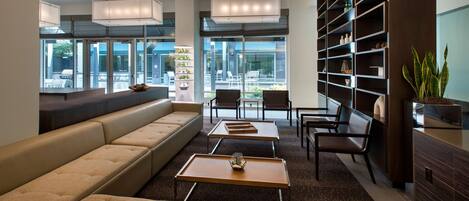 A modern lounge area with a sofa, tables, and a bookshelf.