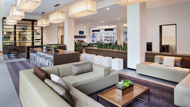 A modern hotel lobby with sofas, a coffee table, and a bar area. - Element by Marriott Boston Seaport District (Boston)