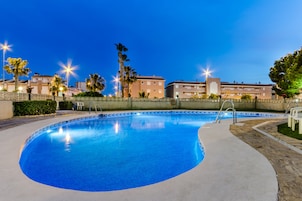 Una piscina al aire libre, sillones reclinables de piscina