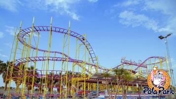Des montagnes russes dans un parc d’attractions, avec un ciel dégagé.