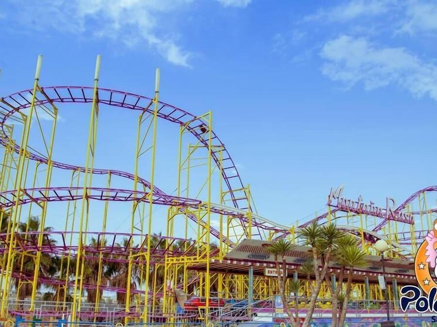 Des montagnes russes dans un parc d’attractions, avec un ciel dégagé.
