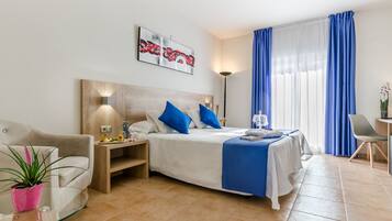 Una habitación de hotel moderna con cama, sofá, mesa de vidrio y una planta en maceta.