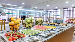 Un bufé con diversas frutas y bollería.