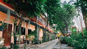 Un sendero bordeado por macetas con plantas y un edificio de estilo arquitectónico tradicional.
