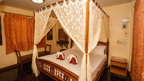 Una cama con dosel, una mesita de noche de madera y una silla.