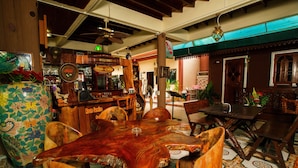 Un comedor de madera tradicional con una mesa grande y sillas, una zona de bar con un letrero que dice 'Café Fresco', y una pared decorativa con un letrero que dice 'Servicio a la habitación'.
