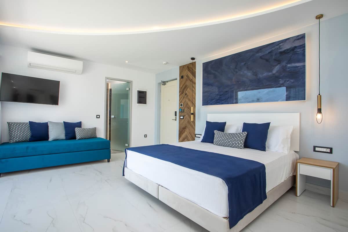 A modern bedroom with a large bed, a blue sofa, and a large abstract painting on the wall.