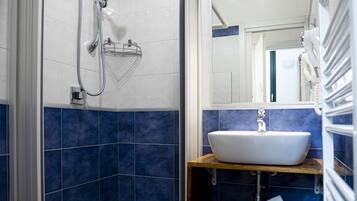 Un baño moderno con cabina de ducha, lavabo y espejo.