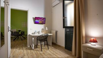 Habitación de hotel compacta con zona de comedor, televisor, lámpara y radiador.