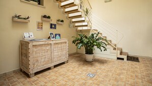 A staircase with a wooden finish, a potted plant, and a wooden cabinet with items on top. - Trapani Home (Trapani)