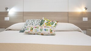 A bed with a white quilt and two decorative pillows with a cactus pattern. - Trapani Home (Trapani)
