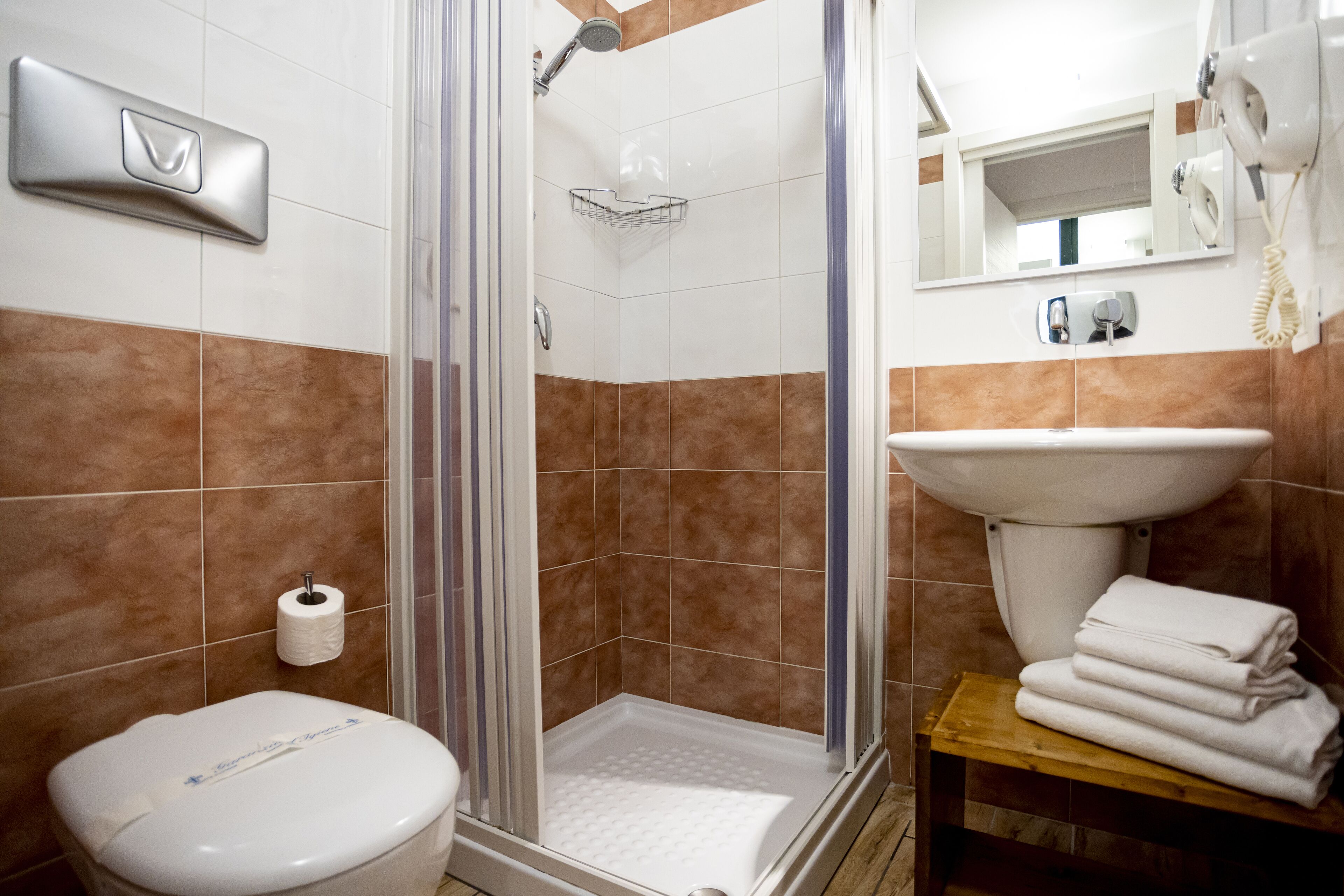 Ein Badezimmer mit Dusche, Toilette, Waschbecken und gestapelten Handtüchern.