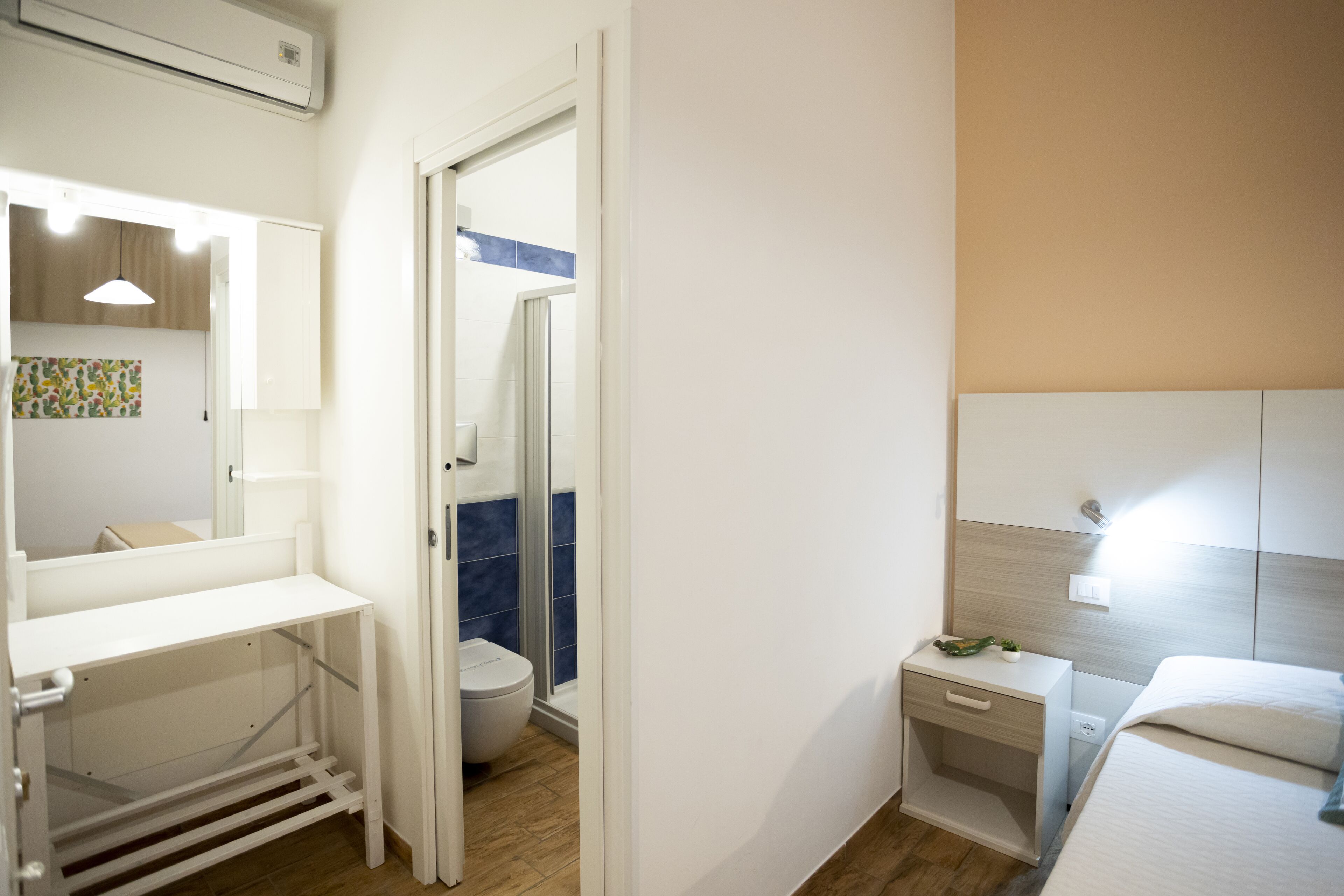 Una habitación de hotel compacta con una cama, mesita de noche y un pequeño escritorio con silla.