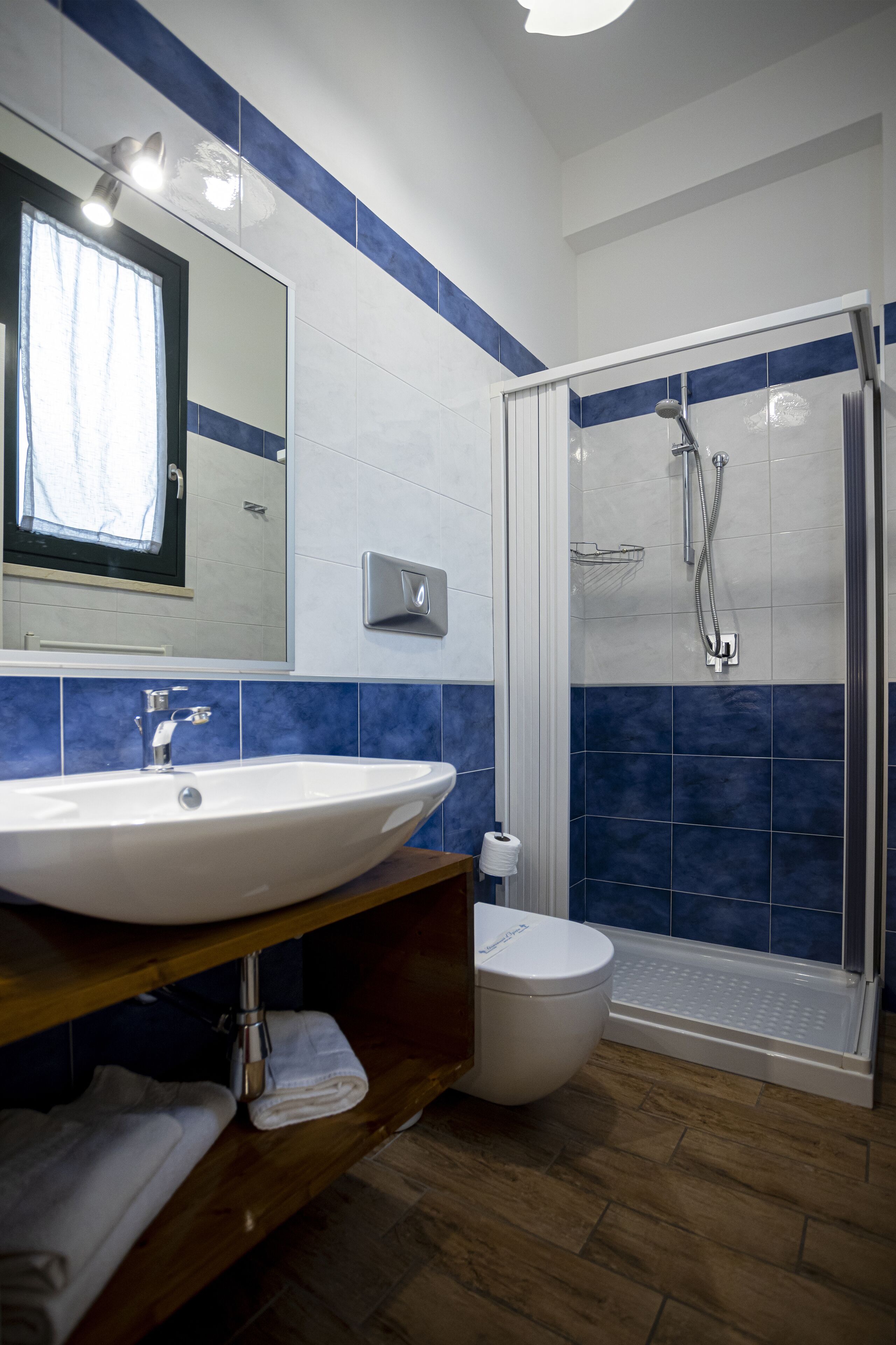 A bathroom with a white sink, a mirror, a toilet, and a shower enclosure.