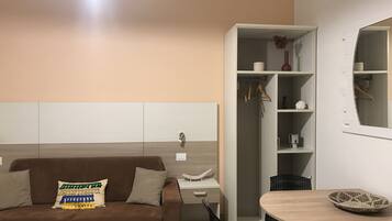 A modern room with a brown sofa, a wooden table, and a white wardrobe with shelves.