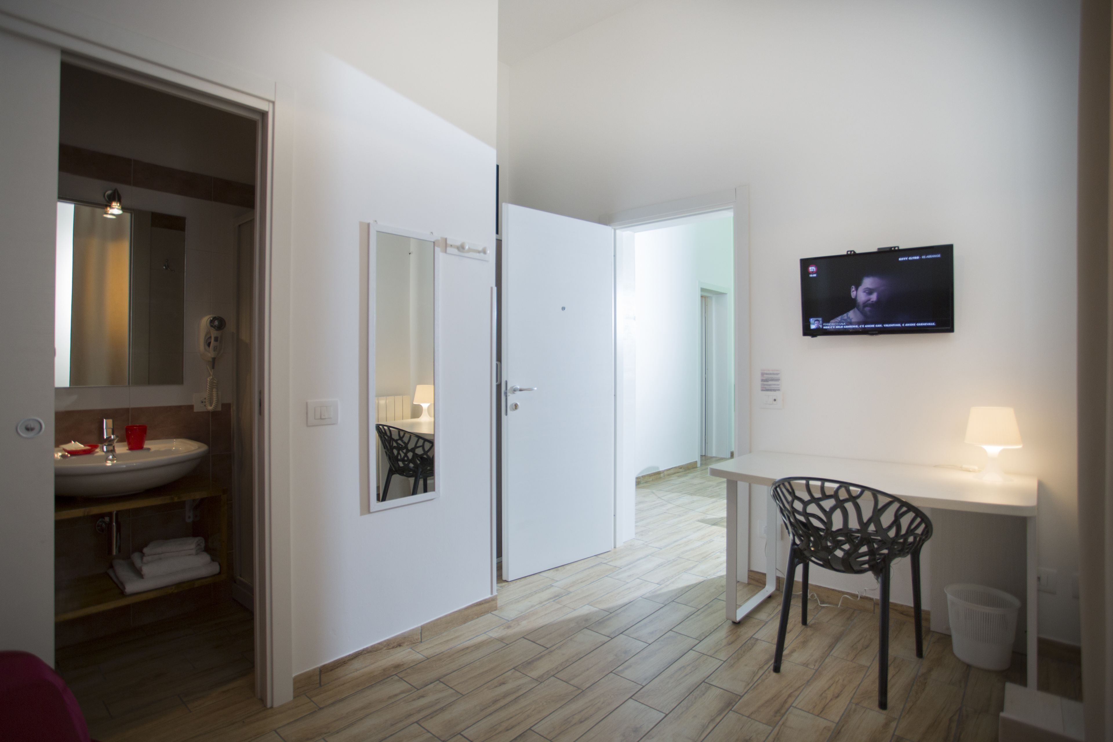 Une chambre d’hôtel moderne dotée d’une salle de bain, d’un téléviseur fixé au mur, d’un bureau et d’une chaise.