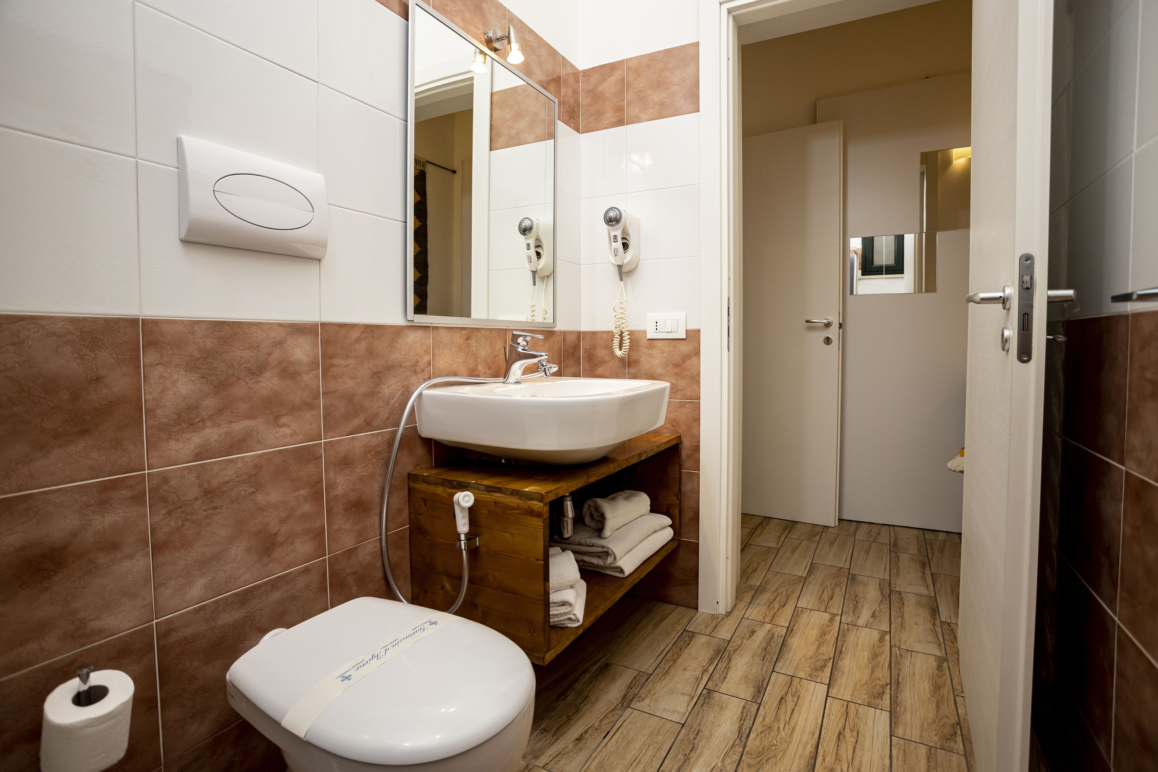 A bathroom with a white sink, a mirror, a towel rack, and a toilet.