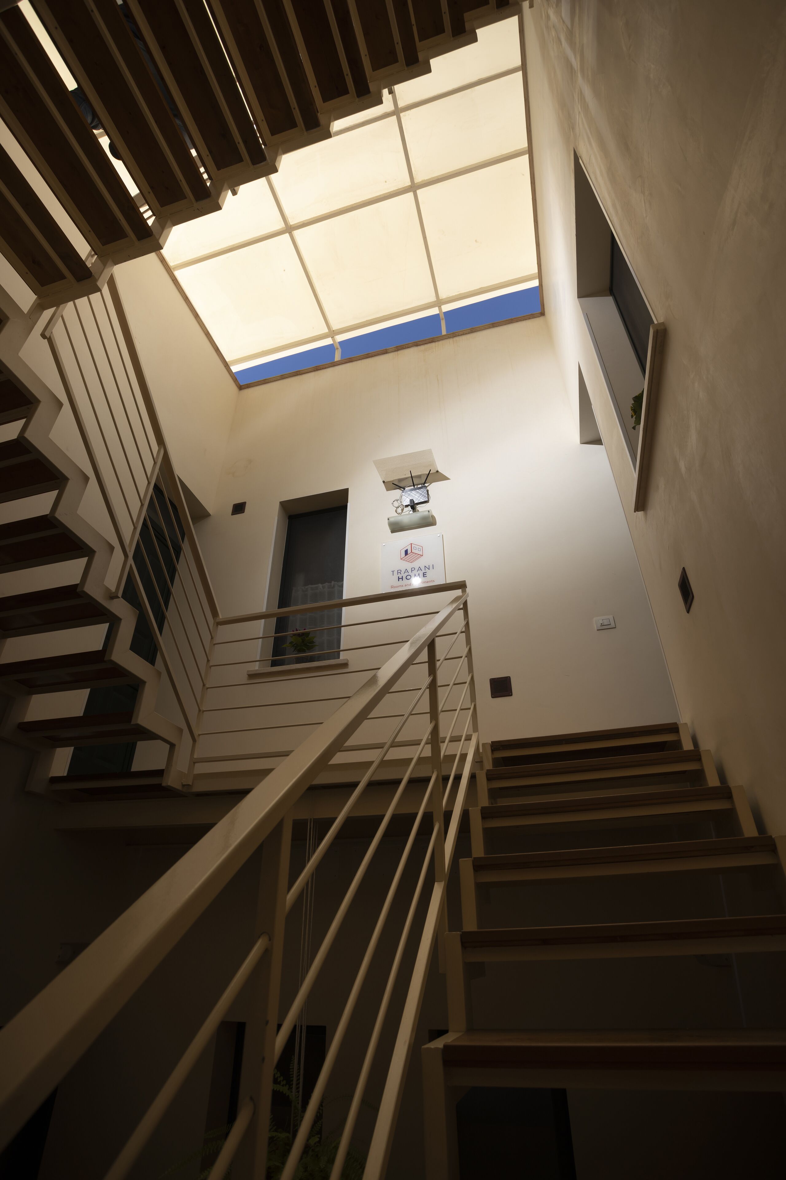 A staircase with a skylight, a sign for "Hotel Rapani," and a small window with a plant.