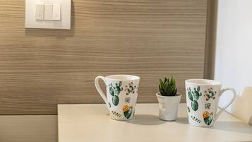 Deux tasses en céramique blanche ornées de motifs de cactus, posées sur une surface en bois.
