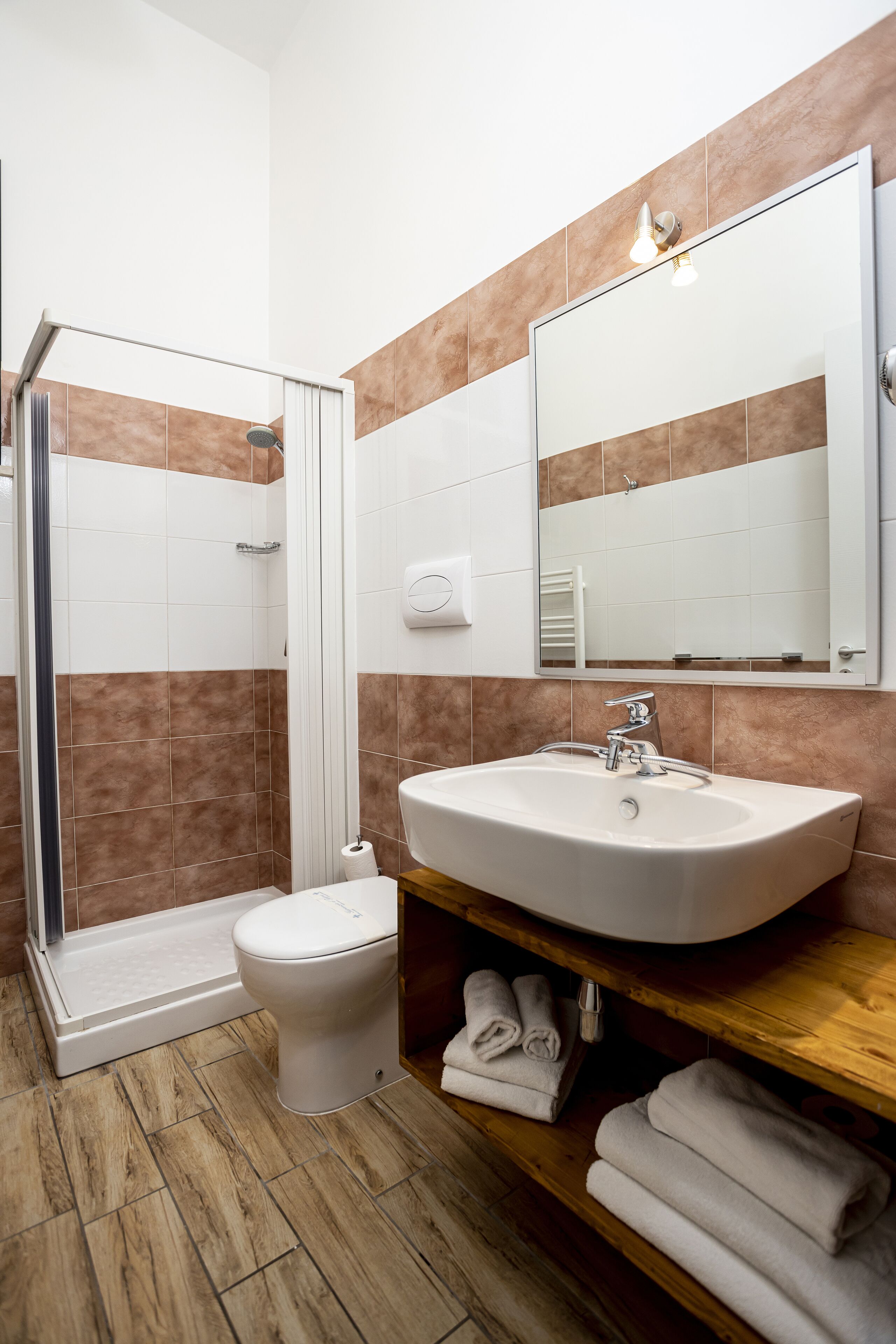 A bathroom with a shower, toilet, sink, and a mirror.