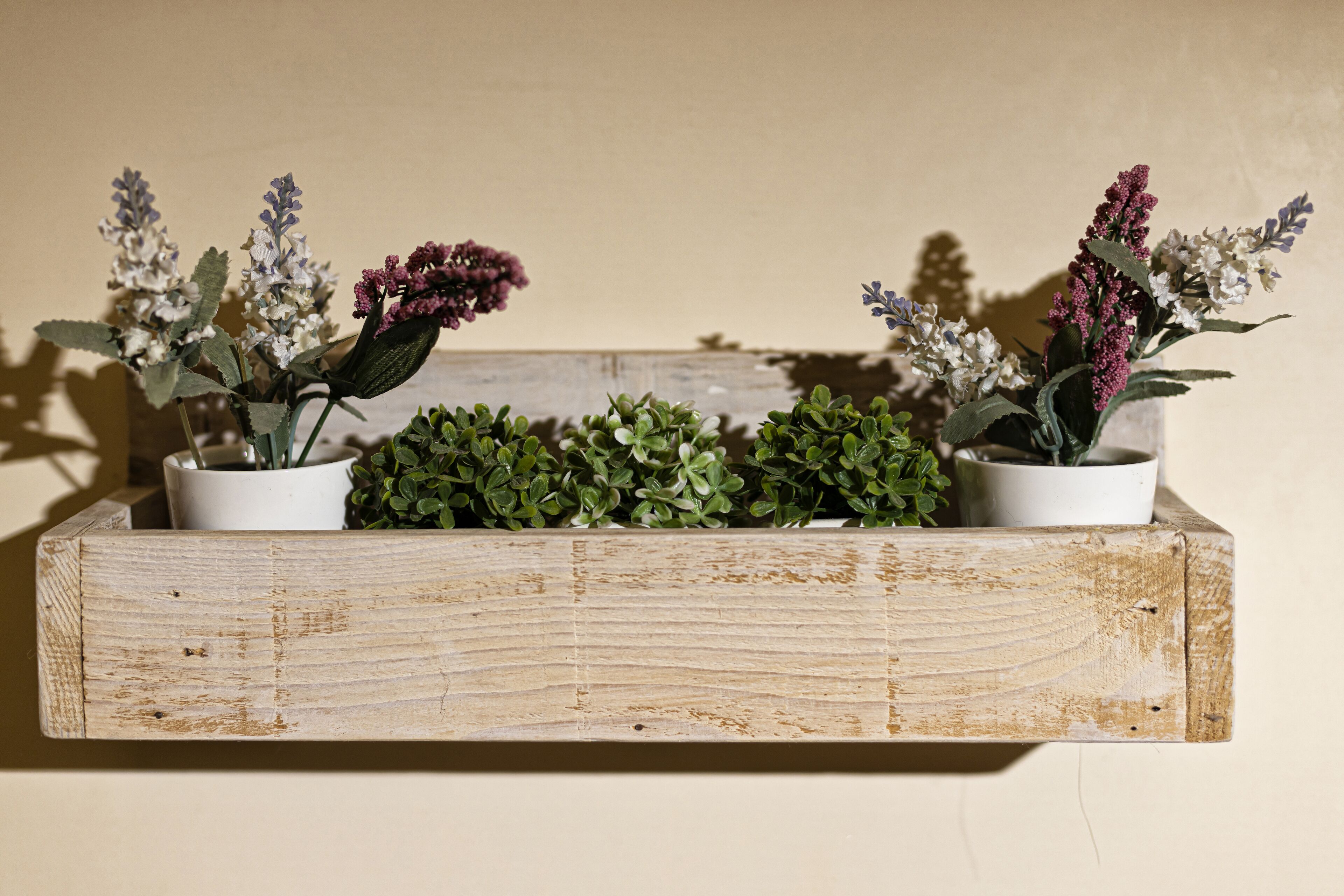 Una repisa de madera con macetas y plantas.