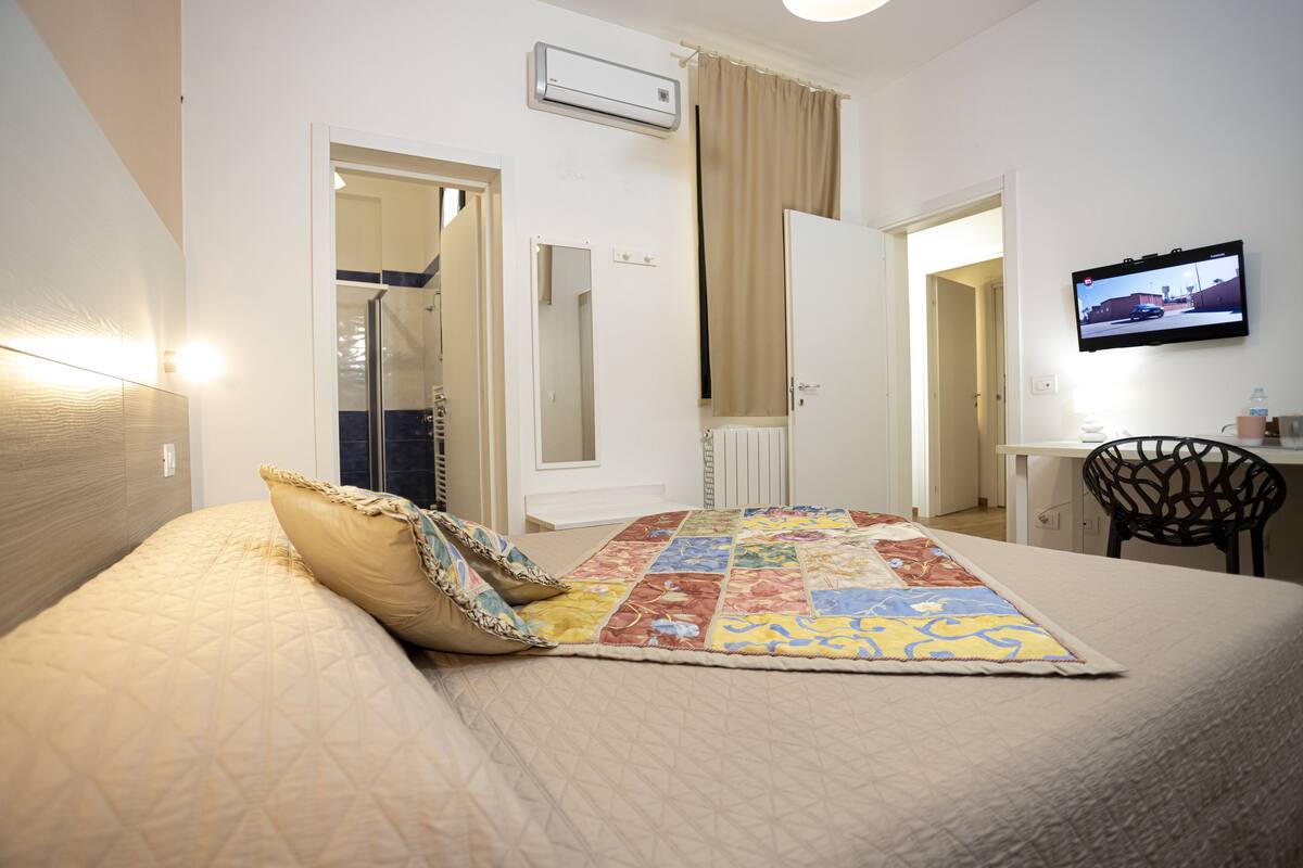 Una habitación de hotel con una cama, un televisor, un escritorio y una silla.