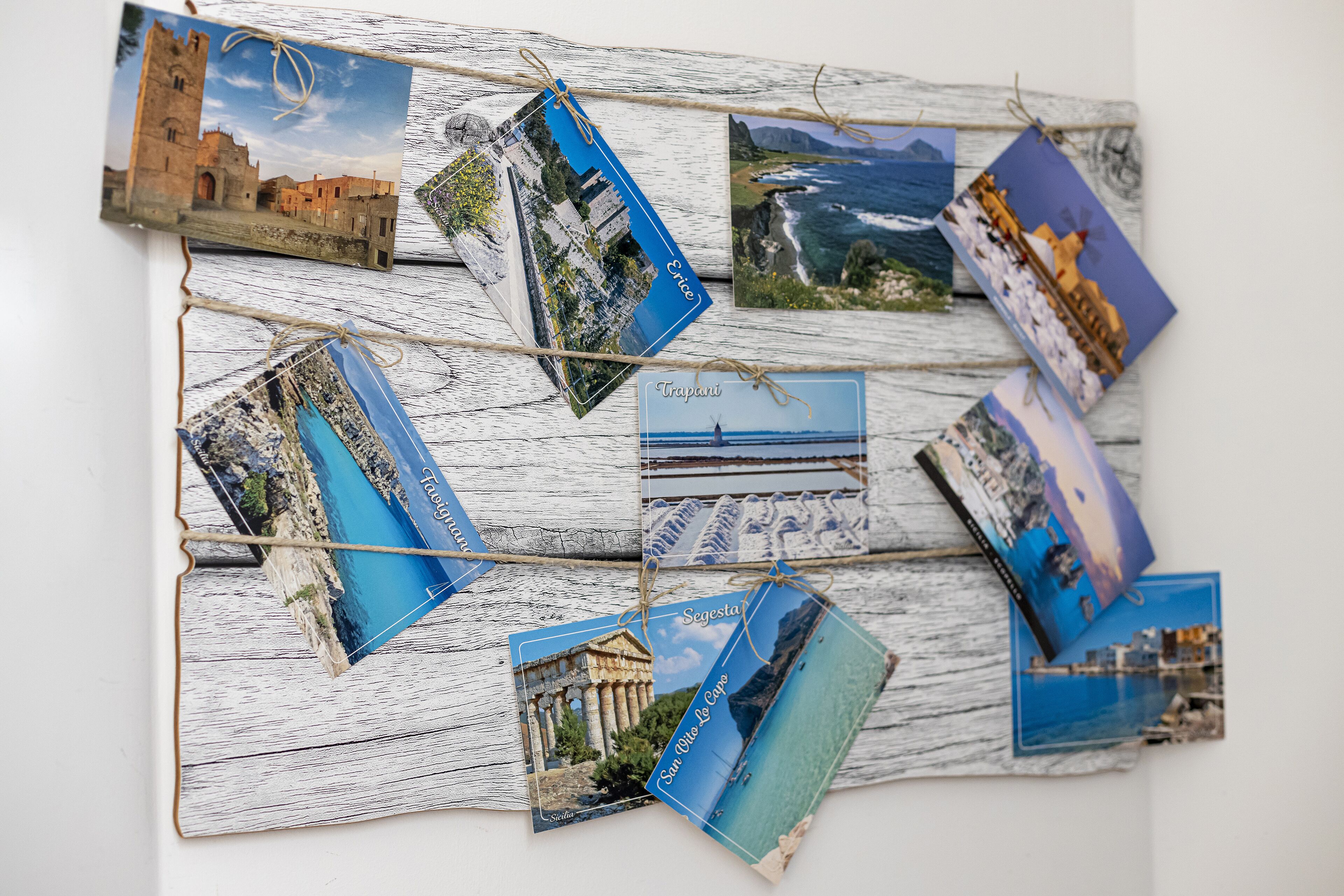 A wall with multiple travel photographs pinned on it, each labeled with a destination name.