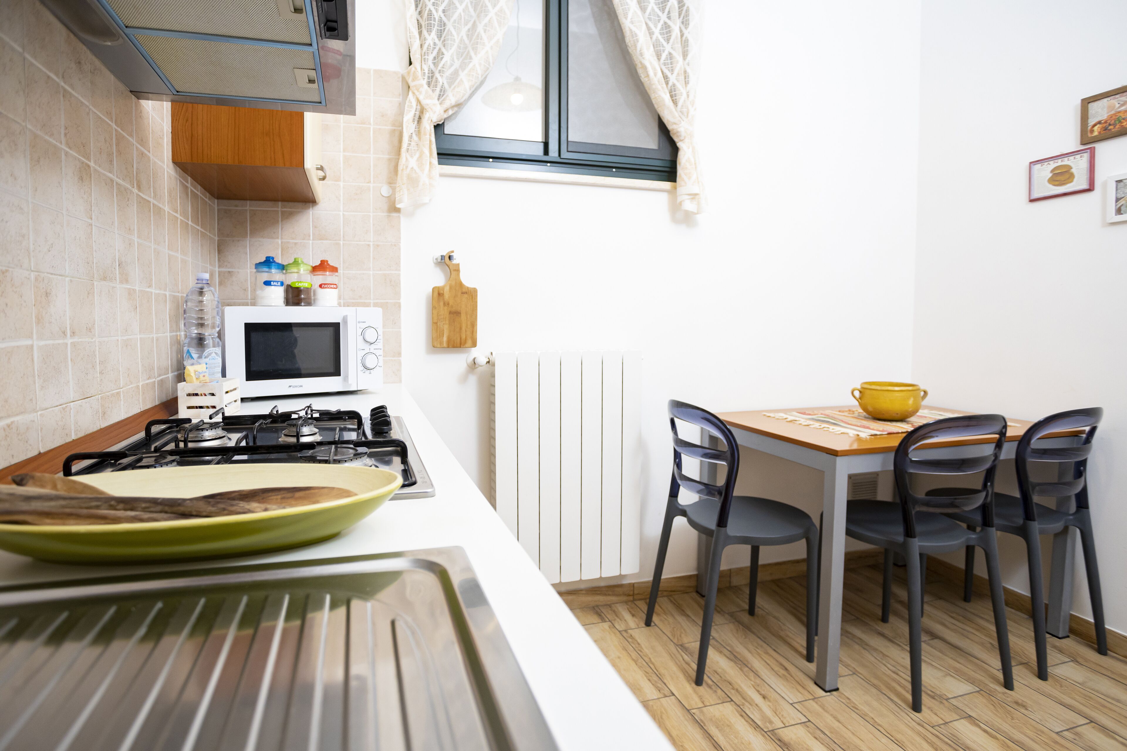 A kitchen with a gas stove, microwave, and a dining table with chairs.