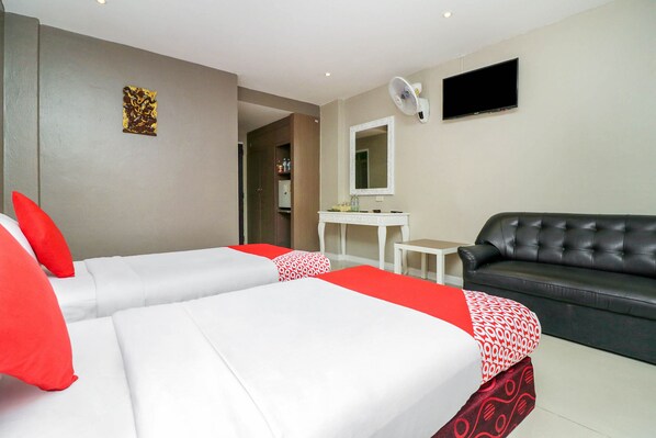 Une chambre d’hôtel avec deux lits, un canapé, une télévision, un miroir et une petite table.