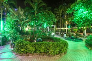 A nighttime garden with illuminated plants and a paved walkway. - Natural Beach Hotel Pattaya (Pattaya)