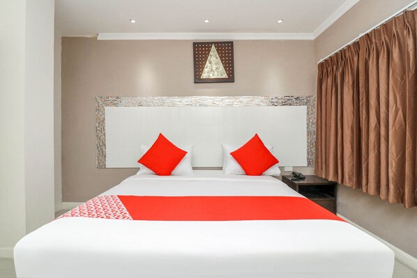 A hotel room with a large bed, a headboard with a decorative panel, and a brown curtain. - Natural Beach Hotel Pattaya (Pattaya)