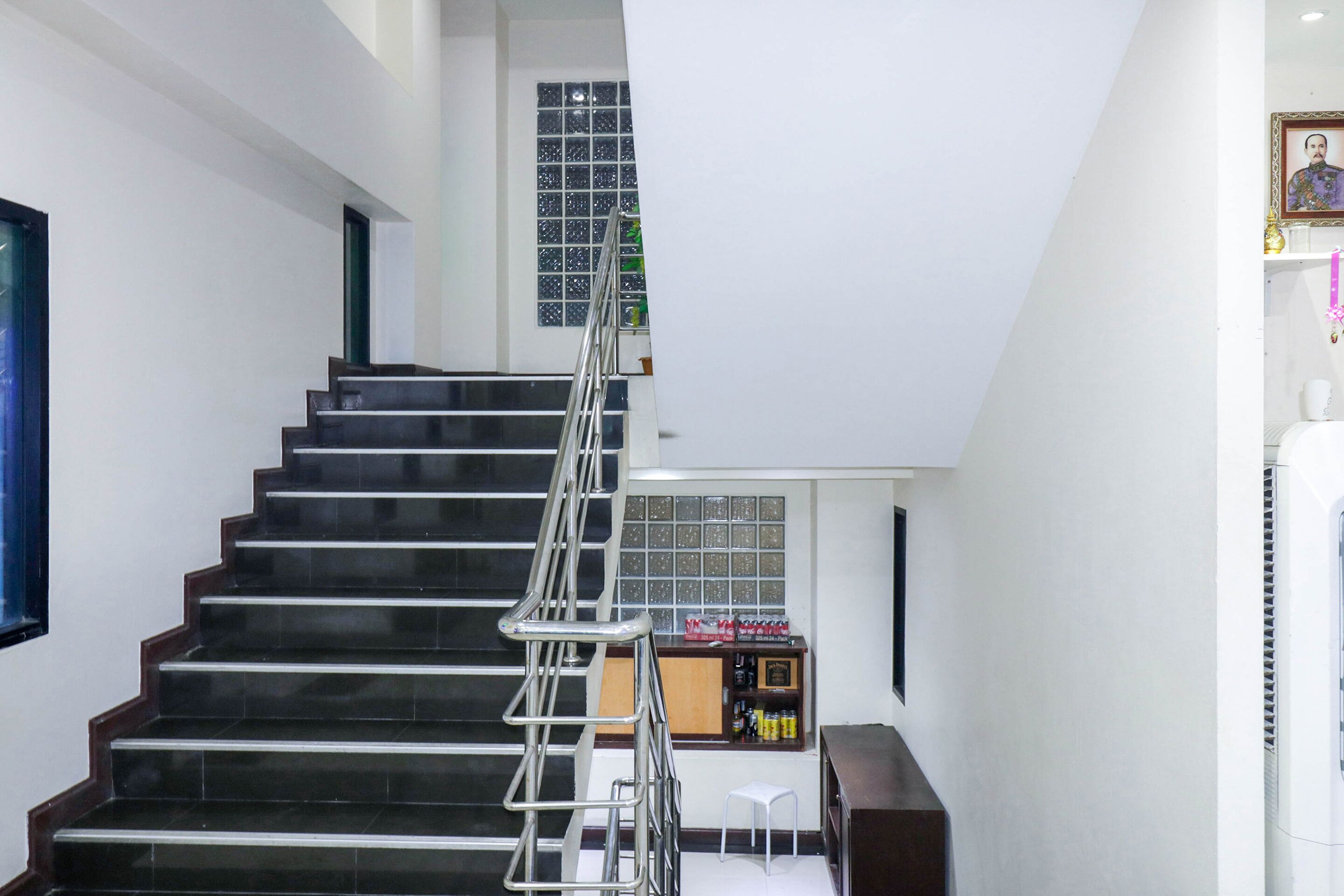 A staircase with a metal handrail leading to a landing with a small table and a chair.