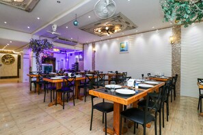 A restaurant with wooden tables and black chairs, a ceiling fan, and decorative wall patterns. - Natural Beach Hotel Pattaya (Pattaya)